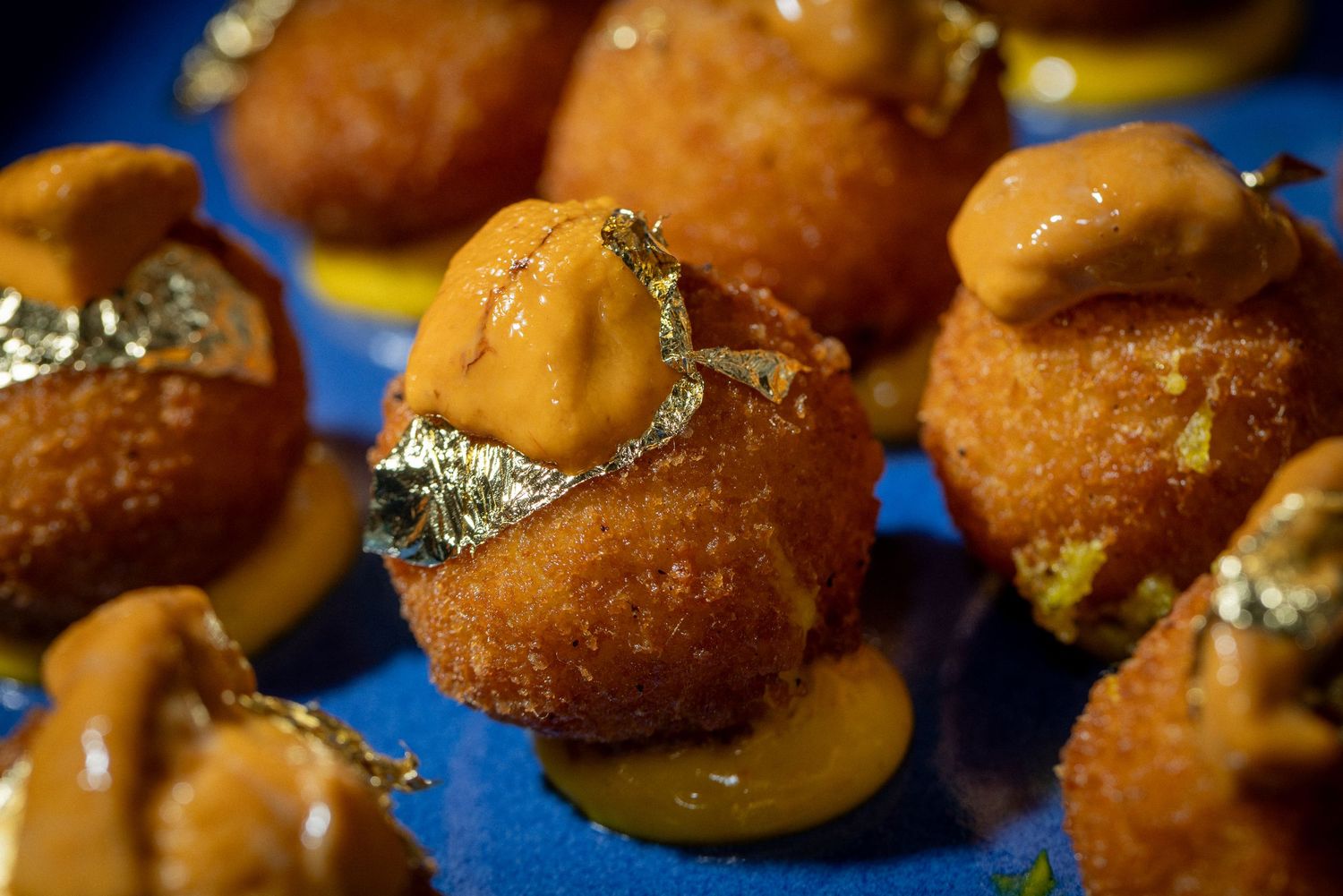 Delicious golden brown sliders topped with melted cheese and caramelized onions on a blue background.