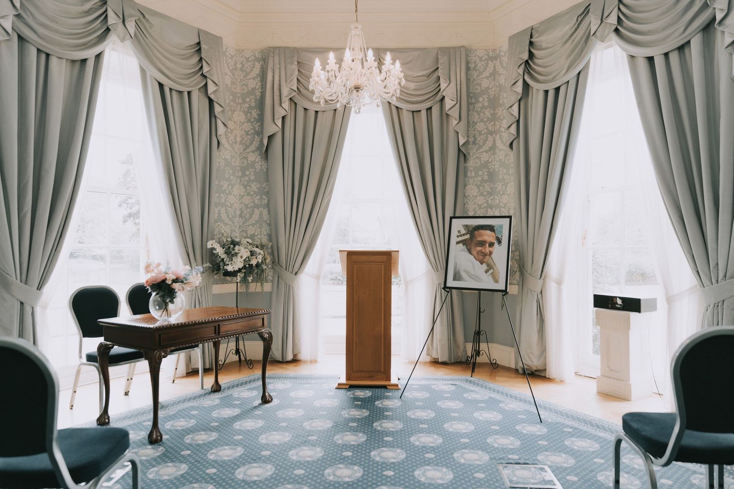 Elegant living room with gray curtains, tall windows, and dark accent chairs arranged in a panoramic view.