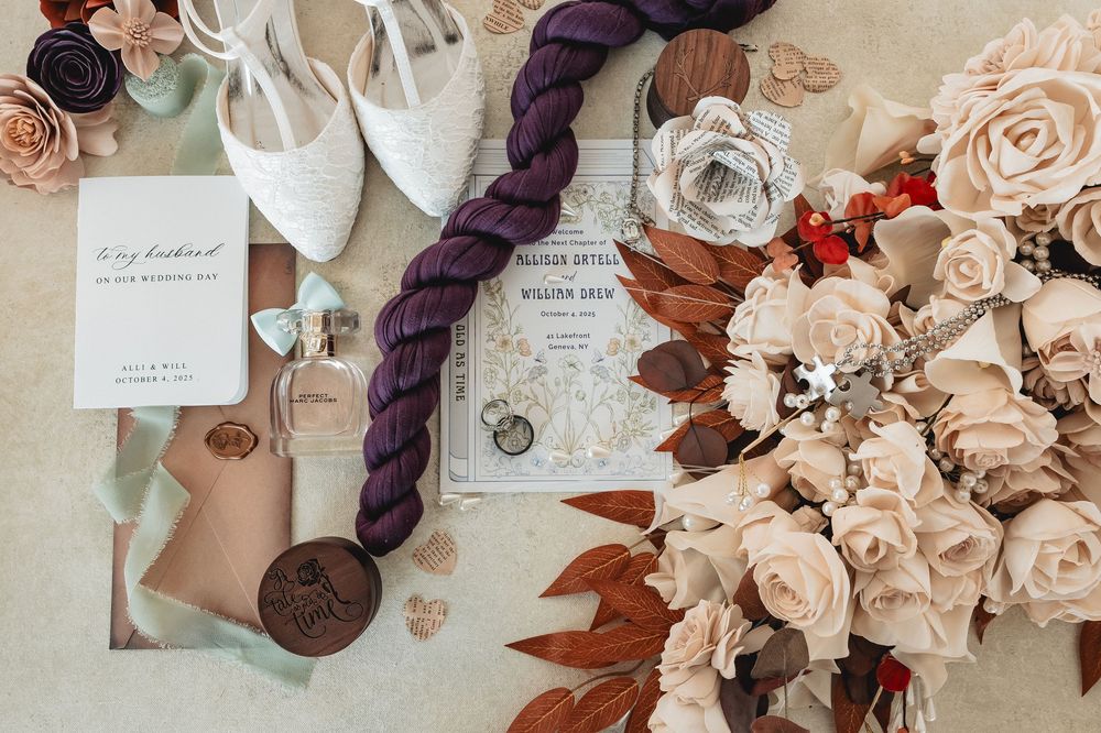Wedding stationery and decor details featuring delicate pink roses and purple accents.