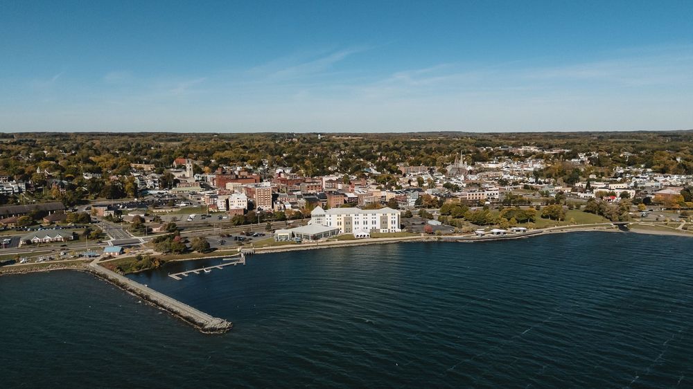 Panoramic aerial view of a coastal town with buildings and waterfront on a clear sunny day.