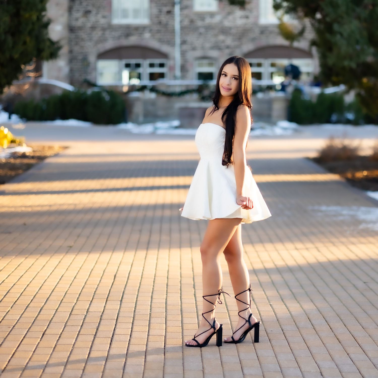 A white mini dress styled with black strappy heels creates an elegant look against brick pavers.