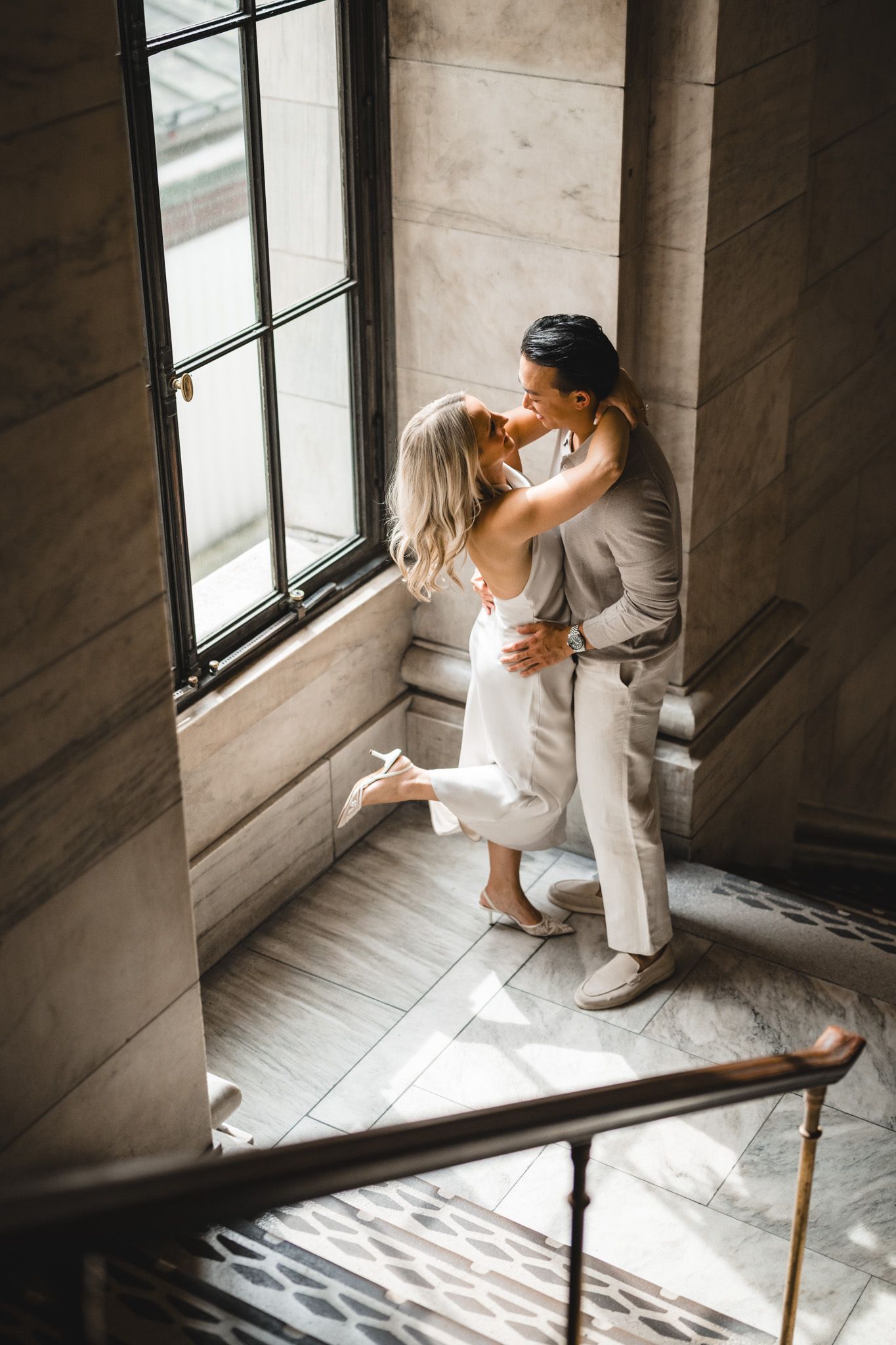 A couple sits by a window in an architectural space with dramatic natural lighting.