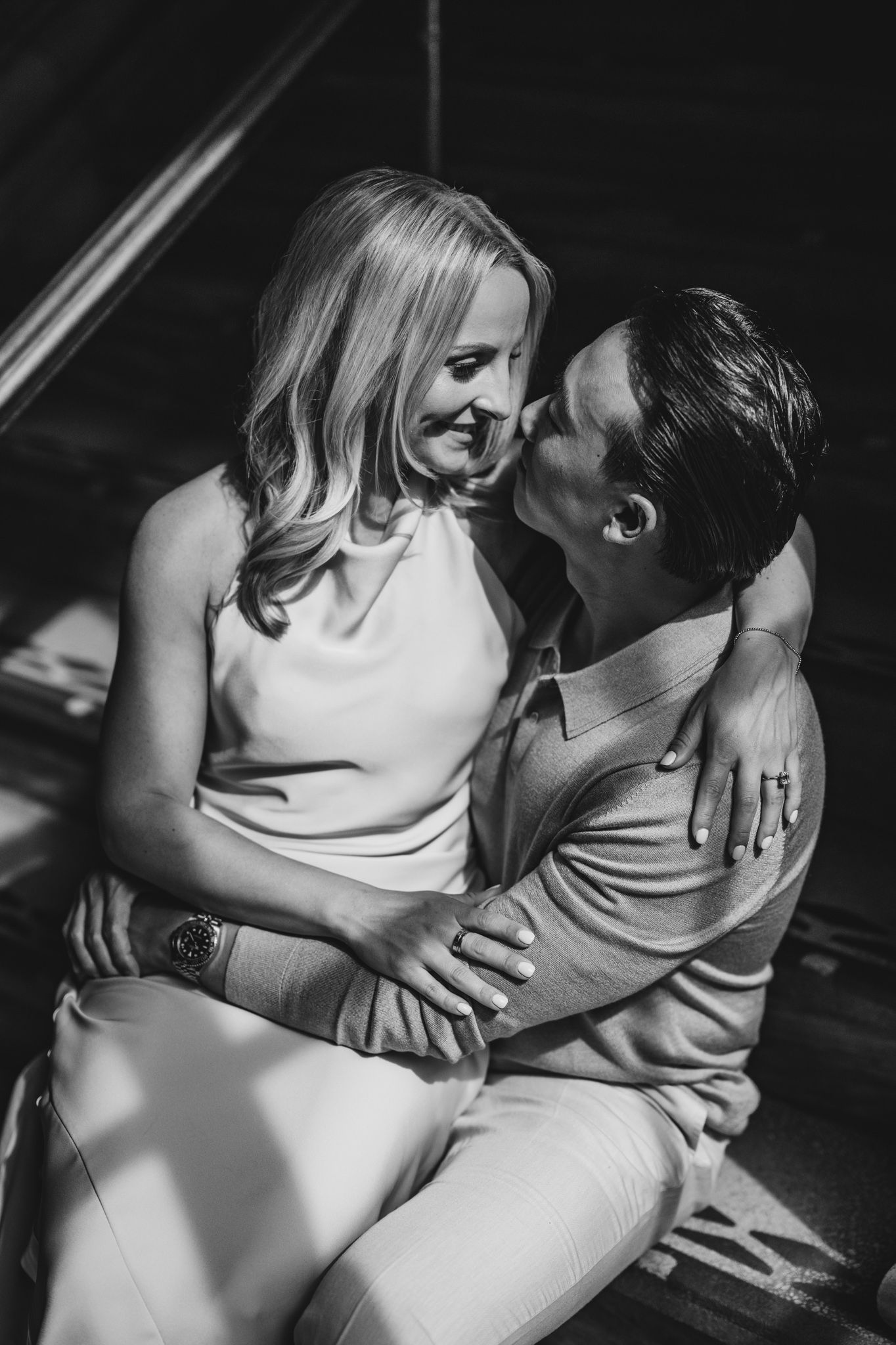 A romantic black and white portrait of a couple embracing in dramatic lighting.