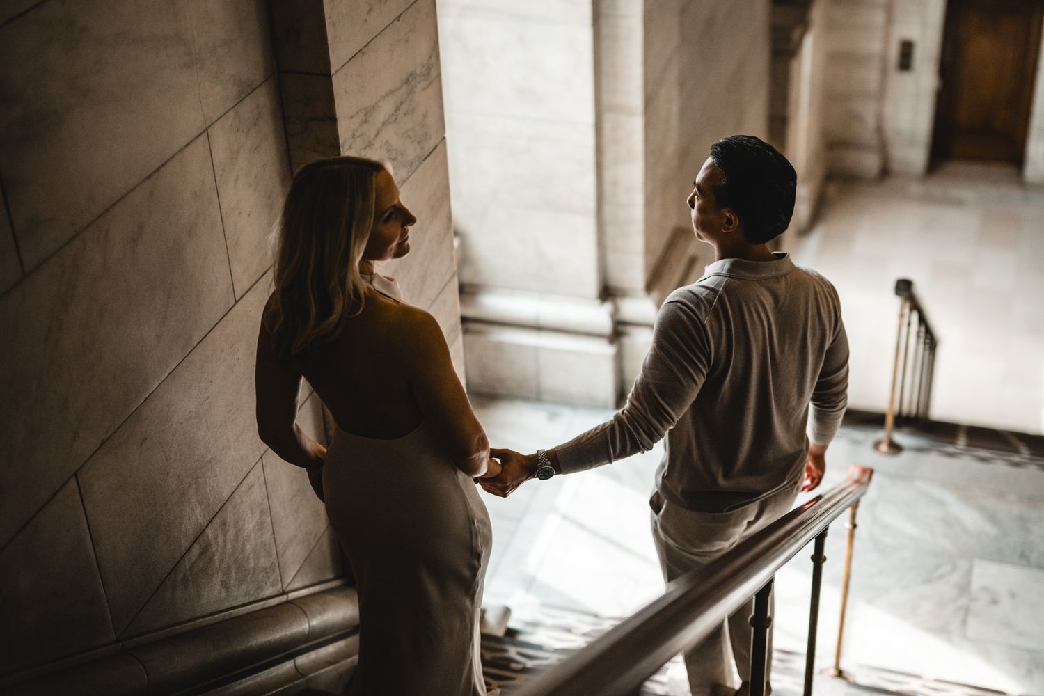 Silhouettes of a couple walking up stairs in a historic building with natural light streaming through.