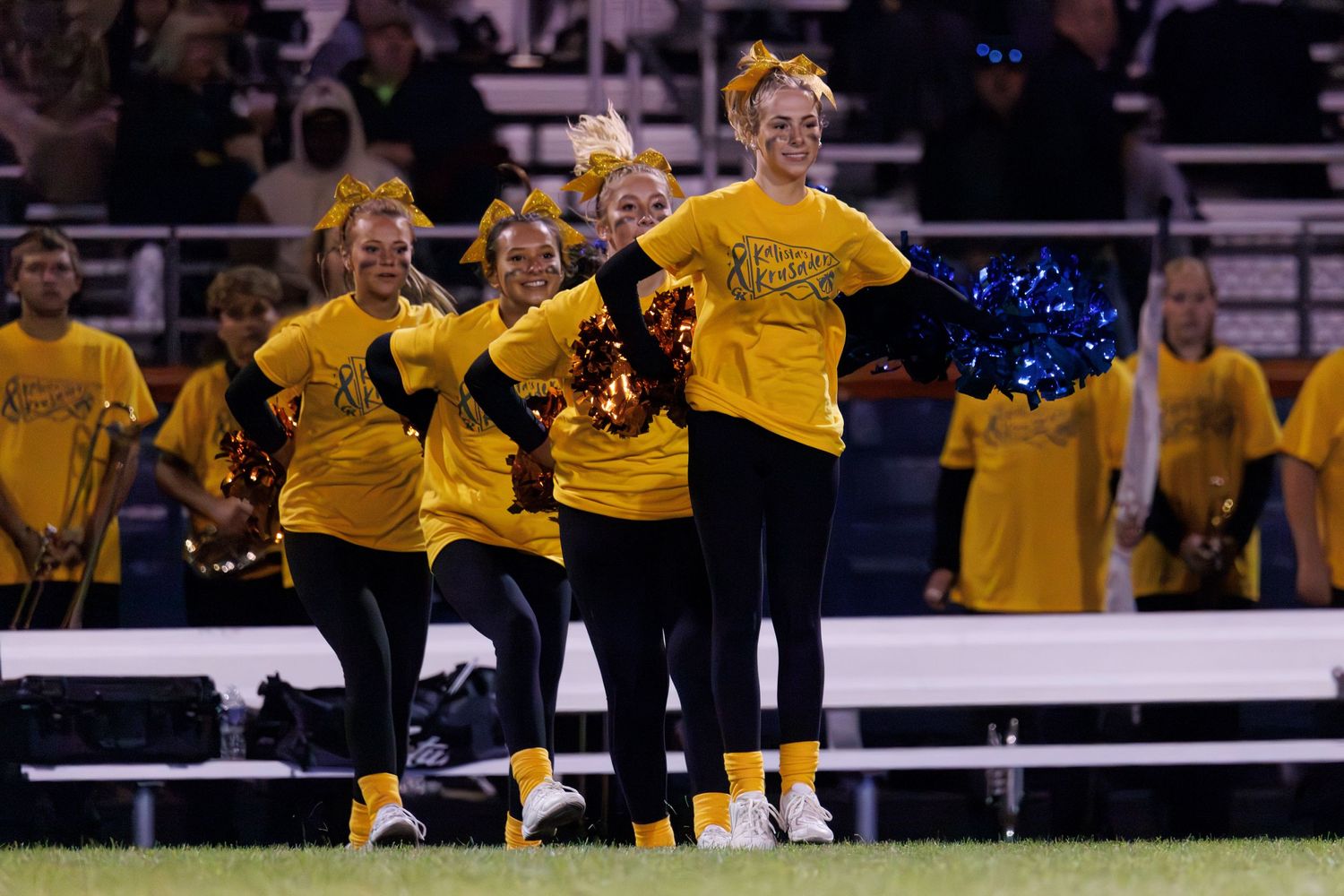 Cheerleaders in yellow uniforms performing at a sports event.