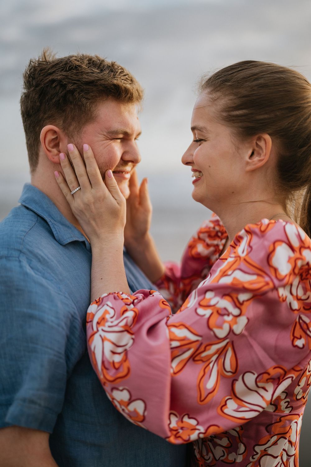 A couple shares a joyful candid moment together while laughing and embracing outdoors.