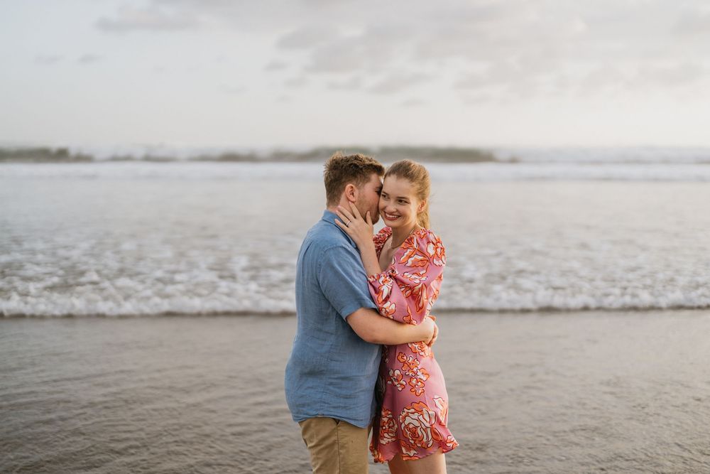 A couple shares a romantic moment together on a misty beach at sunset.