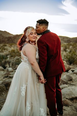A couple shares an intimate moment against a desert landscape backdrop.