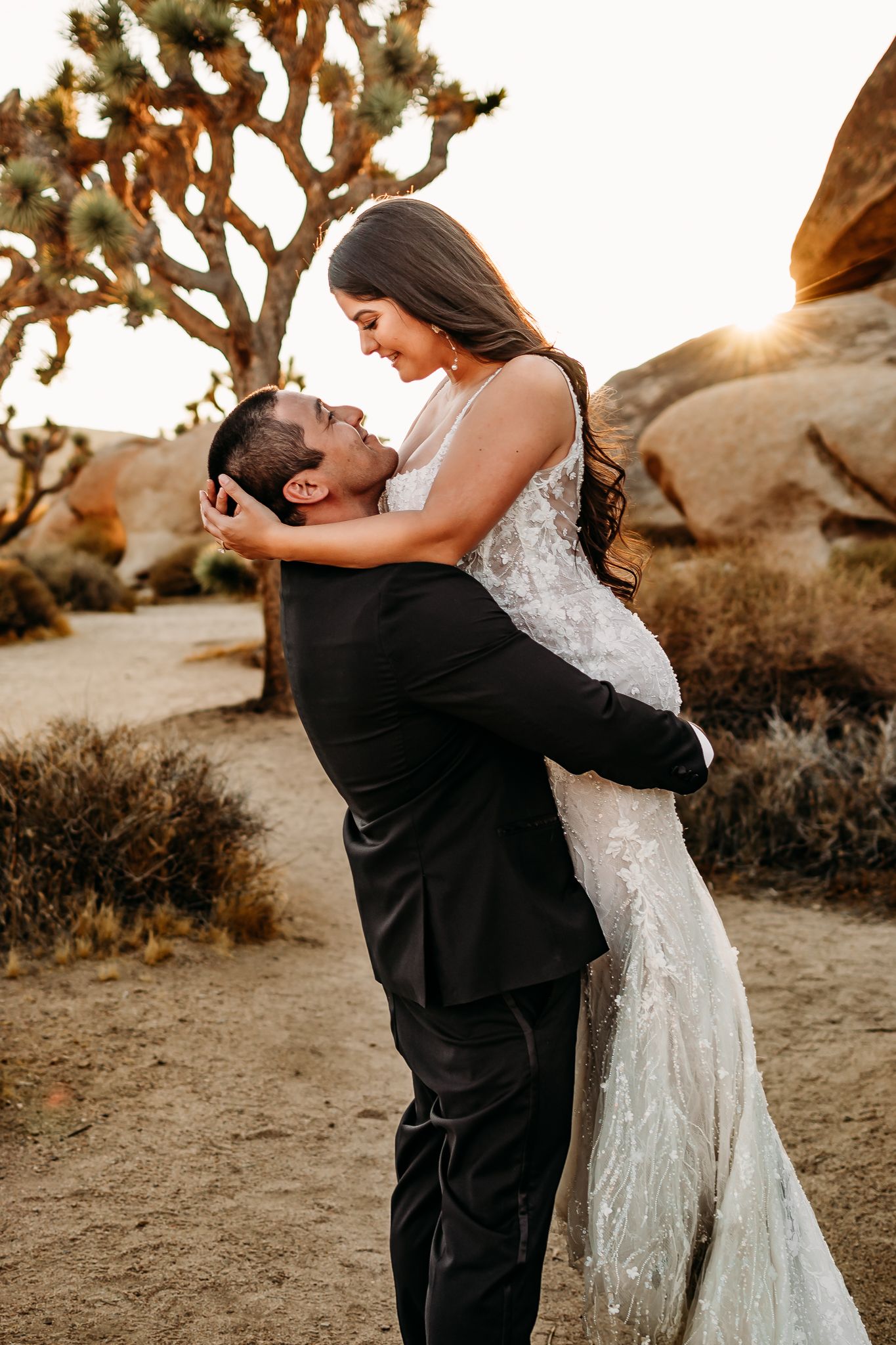 A couple shares a romantic sunset moment in front of a Joshua tree.