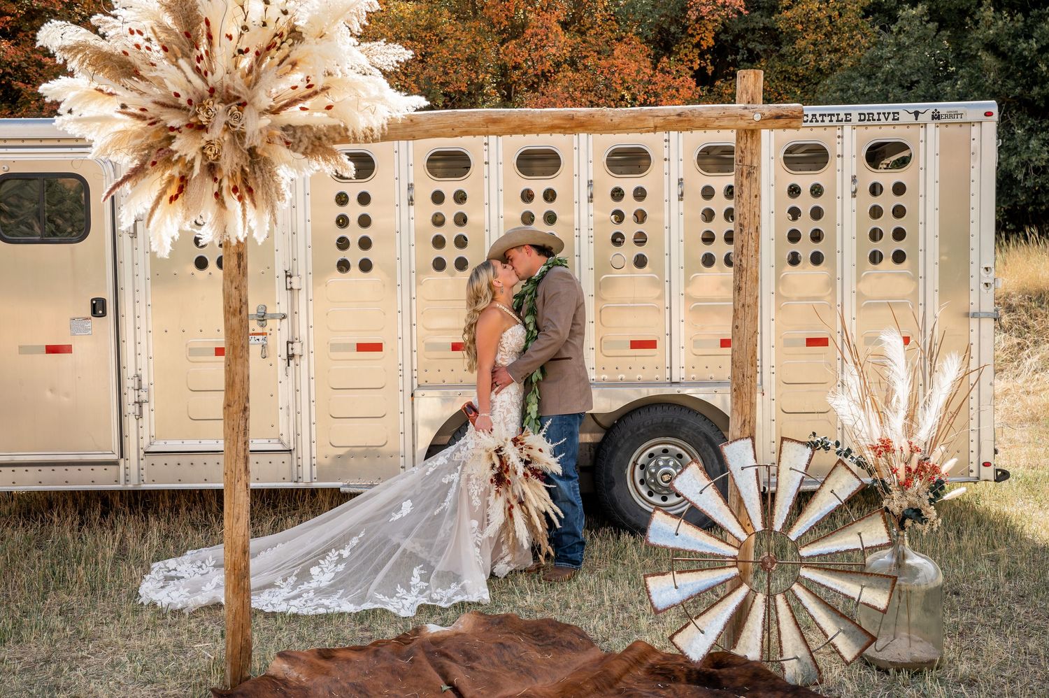 Rustic wedding decor with dried palm fronds and wooden accents against a white building.