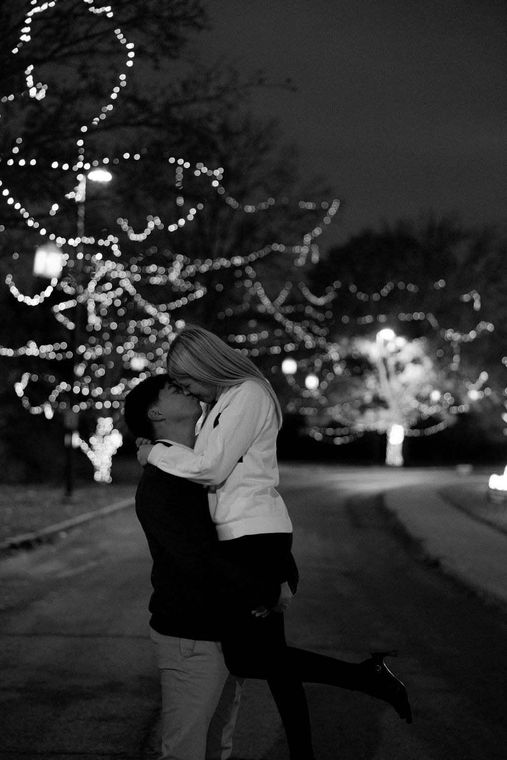 Romantic nighttime scene with string lights illuminating a couple dancing in the snow.