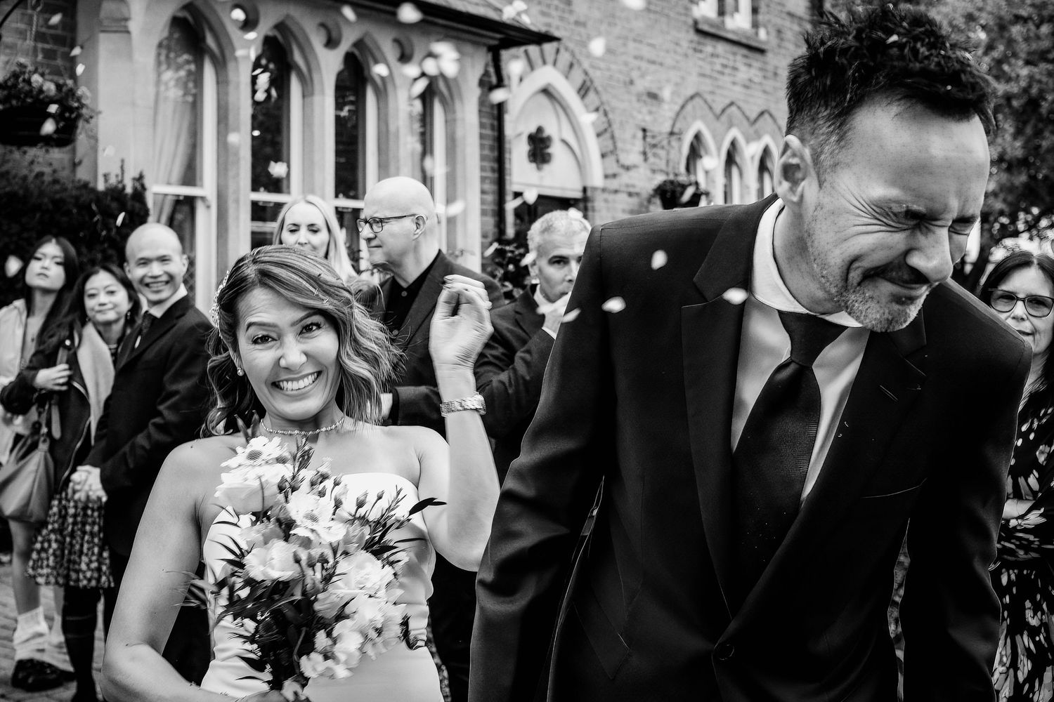 A happy couple walks down the aisle at their wedding ceremony while guests smile and celebrate.
