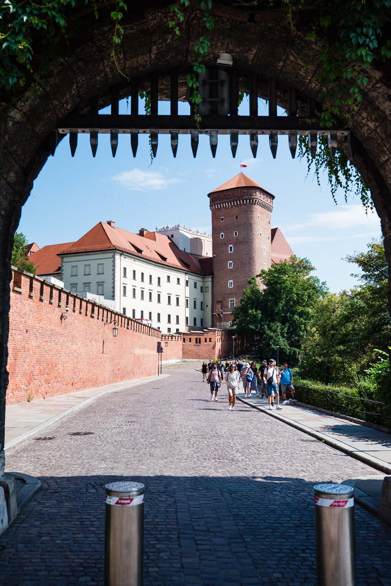 Panoramic view of Wawel Castle's historic stone walls and towers along a cobblestone path in Krakow, Poland.