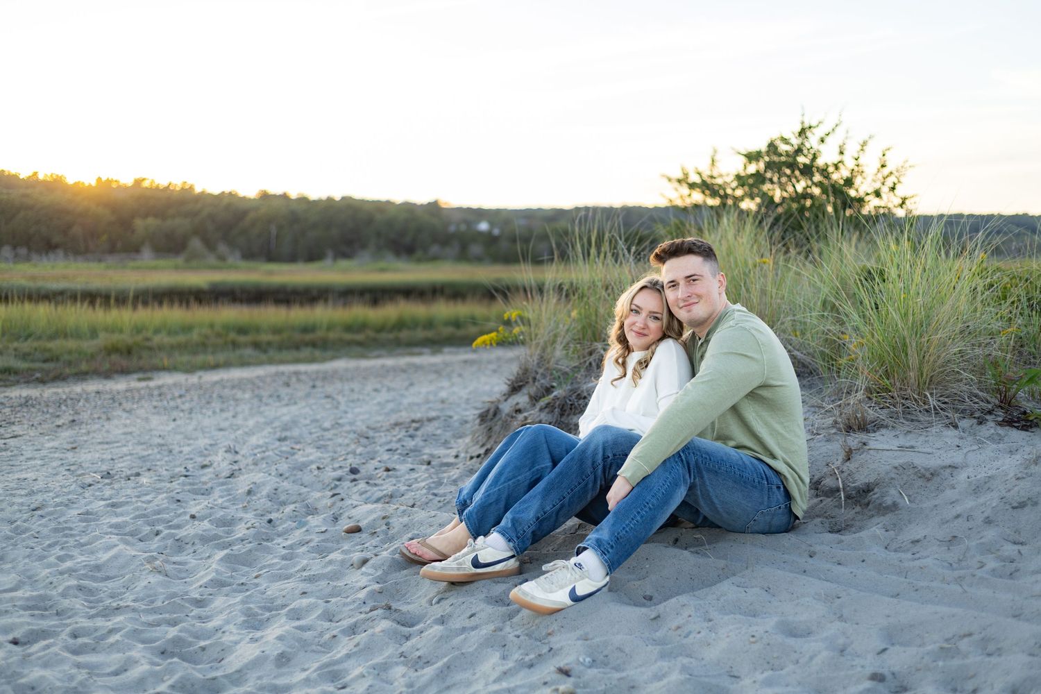 A romantic engagement photo session in a golden marsh field during sunset.