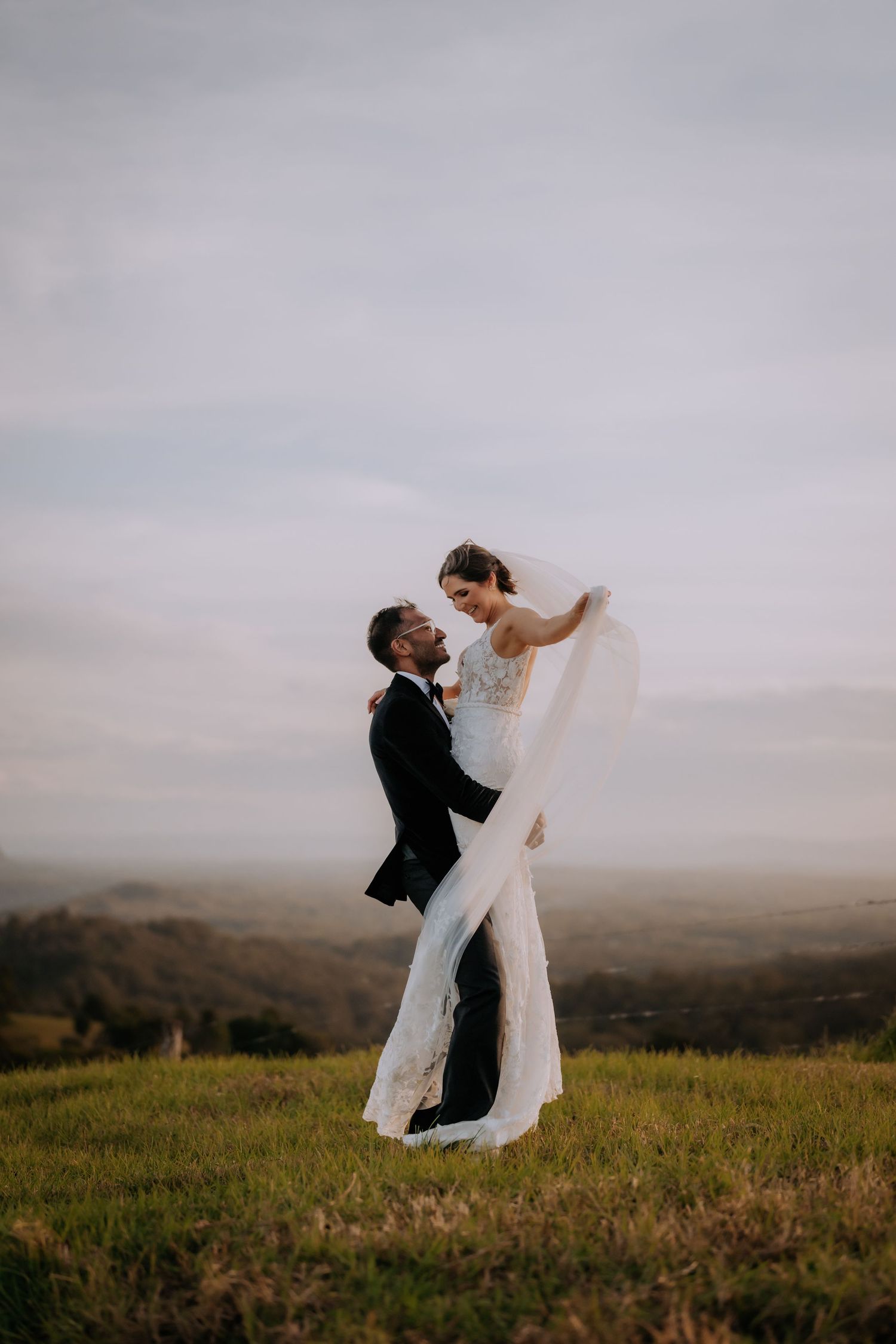 Couple shares romantic moment on hilltop during sunset wedding photoshoot.