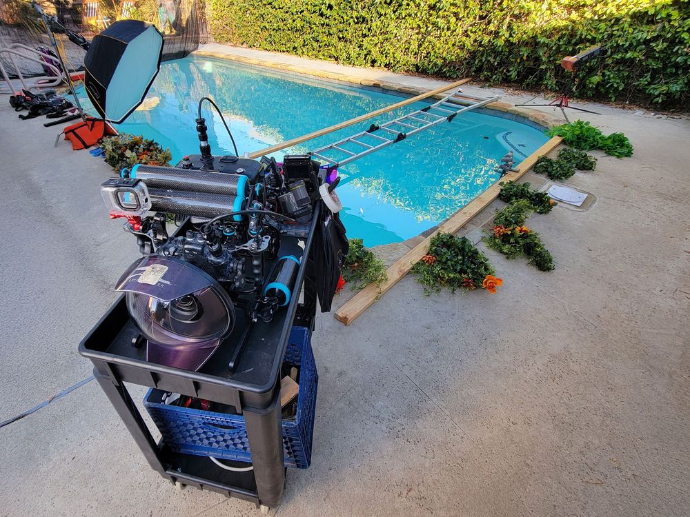 DJ equipment and turntables set up next to a swimming pool during a sunny outdoor party.