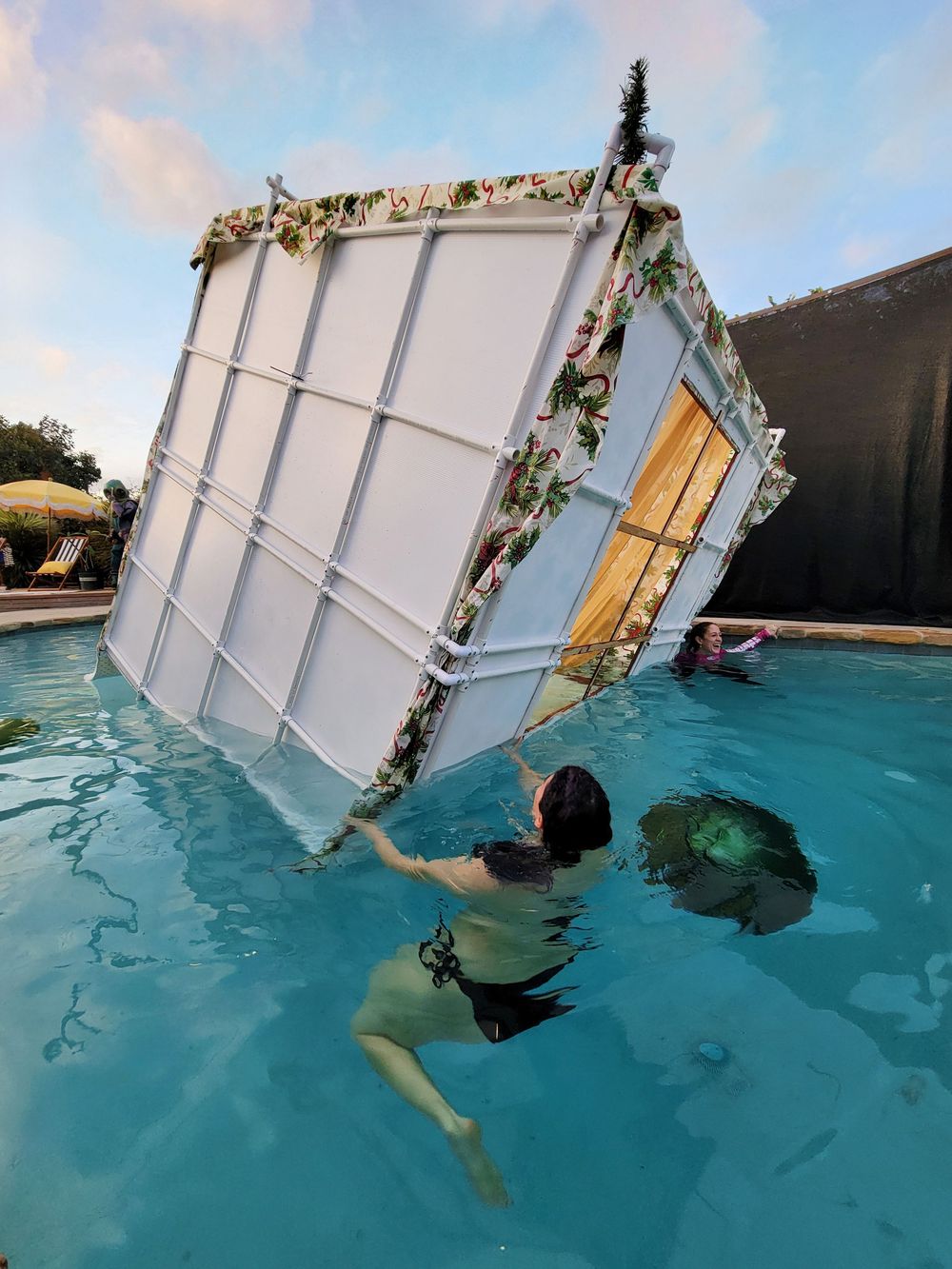 Time-lapse sequence shows a door frame with floral decorations being submerged into a swimming pool.