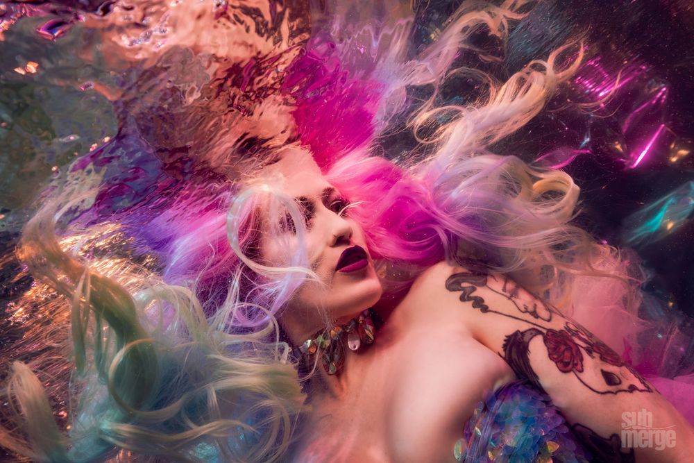 Abstract colorful portrait photography with flowing hair and vibrant pink and purple lighting effects creates ethereal mood.