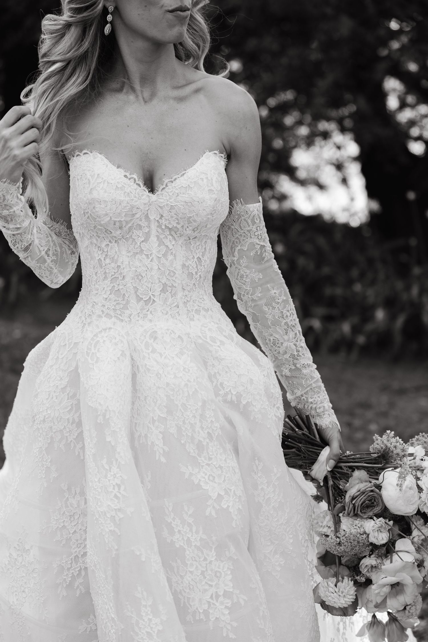 Close-up details of delicate white lace wedding dress with sweetheart neckline and intricate floral embroidery patterns.