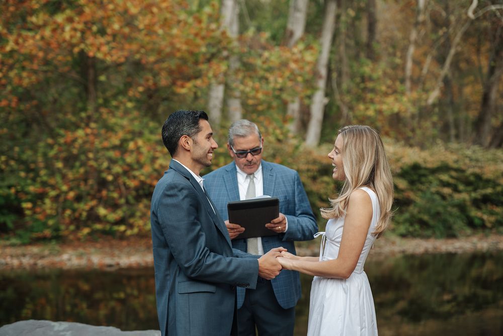A couple celebrates their wedding day in a beautiful autumn forest setting with golden leaves surrounding them.