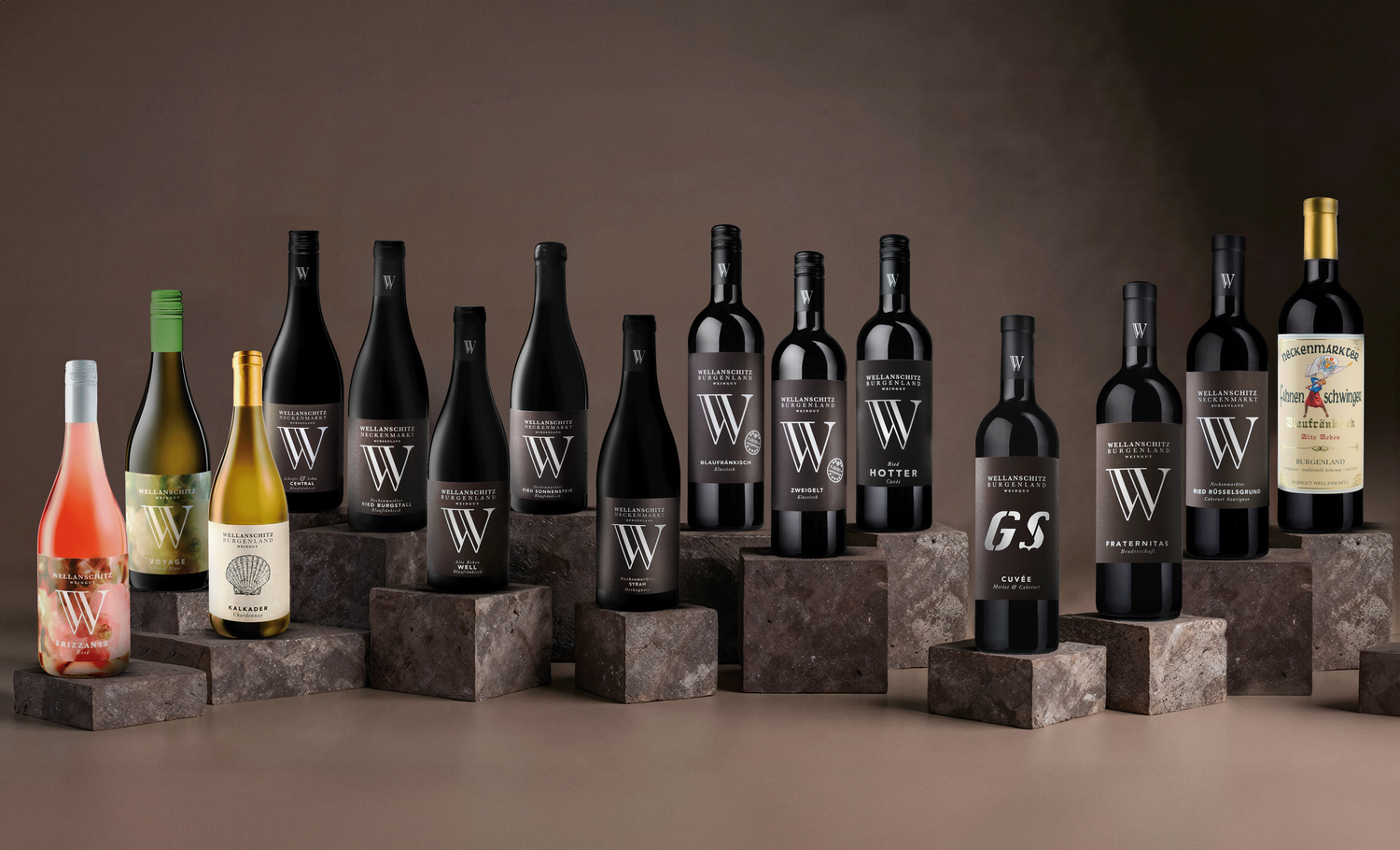 Collection of premium wine bottles displayed on stone pedestals against brown background.