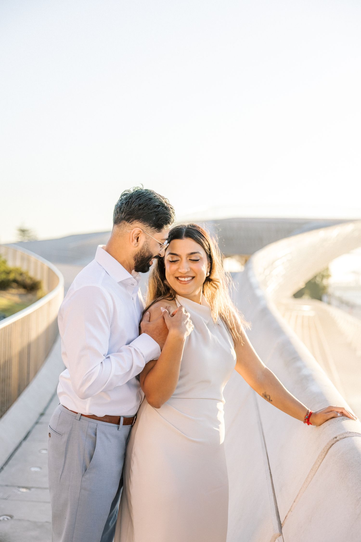 Joyful moment between couple laughing by the riverside at MAAT during sunrise engagement shoot, taken by a portugal wedding photographer
