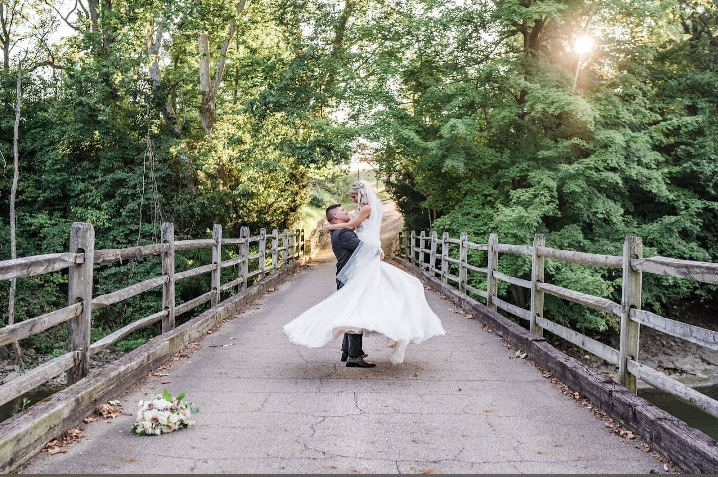 Rustic wooden bridge pathway surrounded by lush trees for an outdoor wedding ceremony.