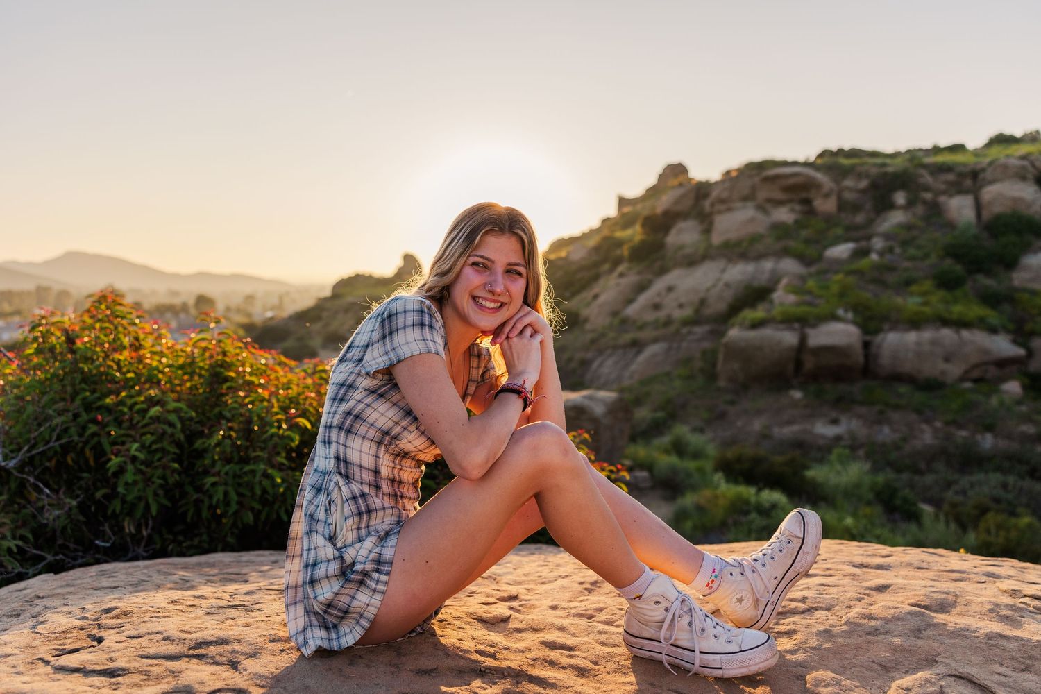 A couple shares a romantic moment at sunset on a rocky cliff overlooking the ocean.