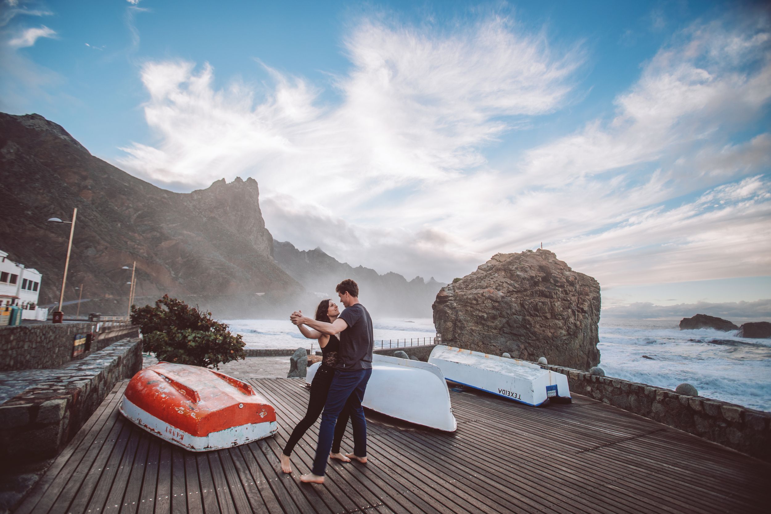 A romantic photoshoot on a wooden boardwalk overlooking dramatic coastal cliffs.
