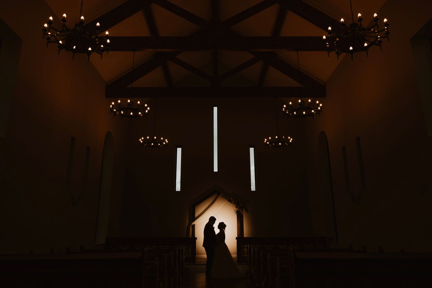 String lights illuminate a rustic wooden barn interior during an evening wedding reception.