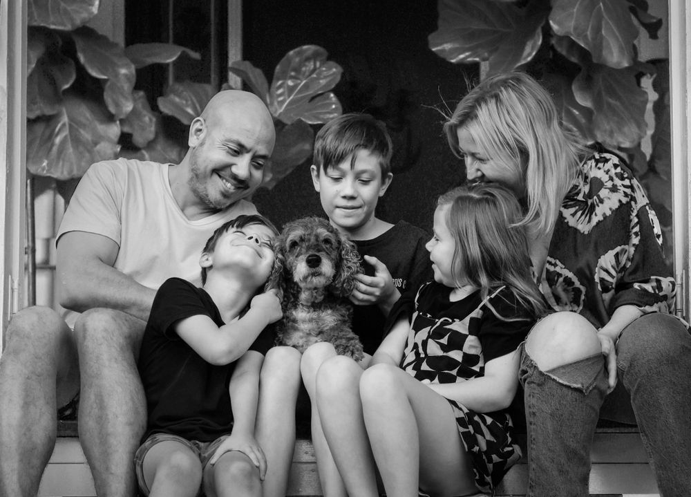 Group of people sitting together on porch steps in black and white.
