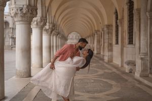 A romantic couple poses in an elegant architectural archway with columns and ornate details in Venice, Italy.