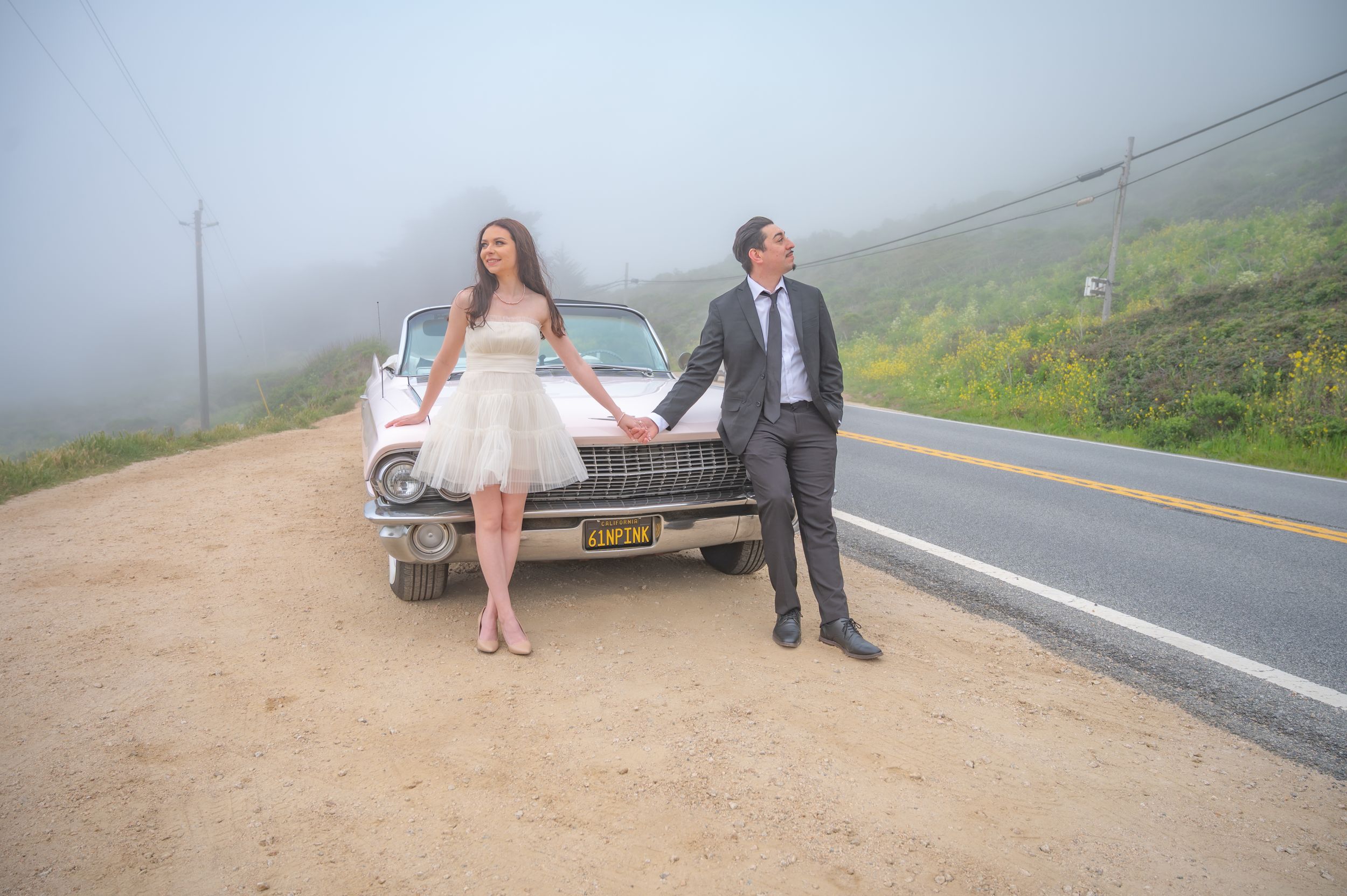 Couple sitting together on wooden bench in foggy mountain setting during romantic photo session.