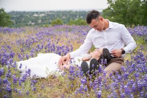 A couple relaxes together in a beautiful purple wildflower meadow on a sunny spring afternoon.