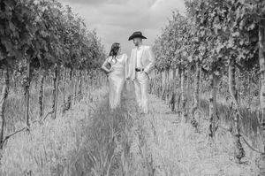 Black and white photograph showing two figures walking through rows of grapevines in a vineyard circa 1920s.