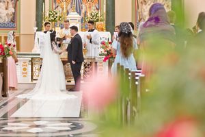 Elegant church wedding ceremony with bride in white gown and groom at the altar, guests seated in pews.