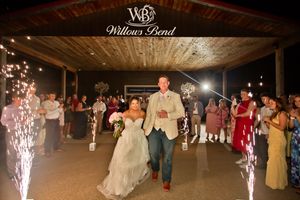 Bride and groom exit wedding reception at Willows Bend venue amid sparkling fountains with guests lining the path.