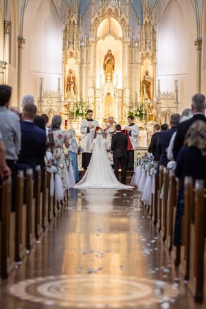 A bride and groom exchange vows at a grand ornate church altar during a traditional wedding ceremony.