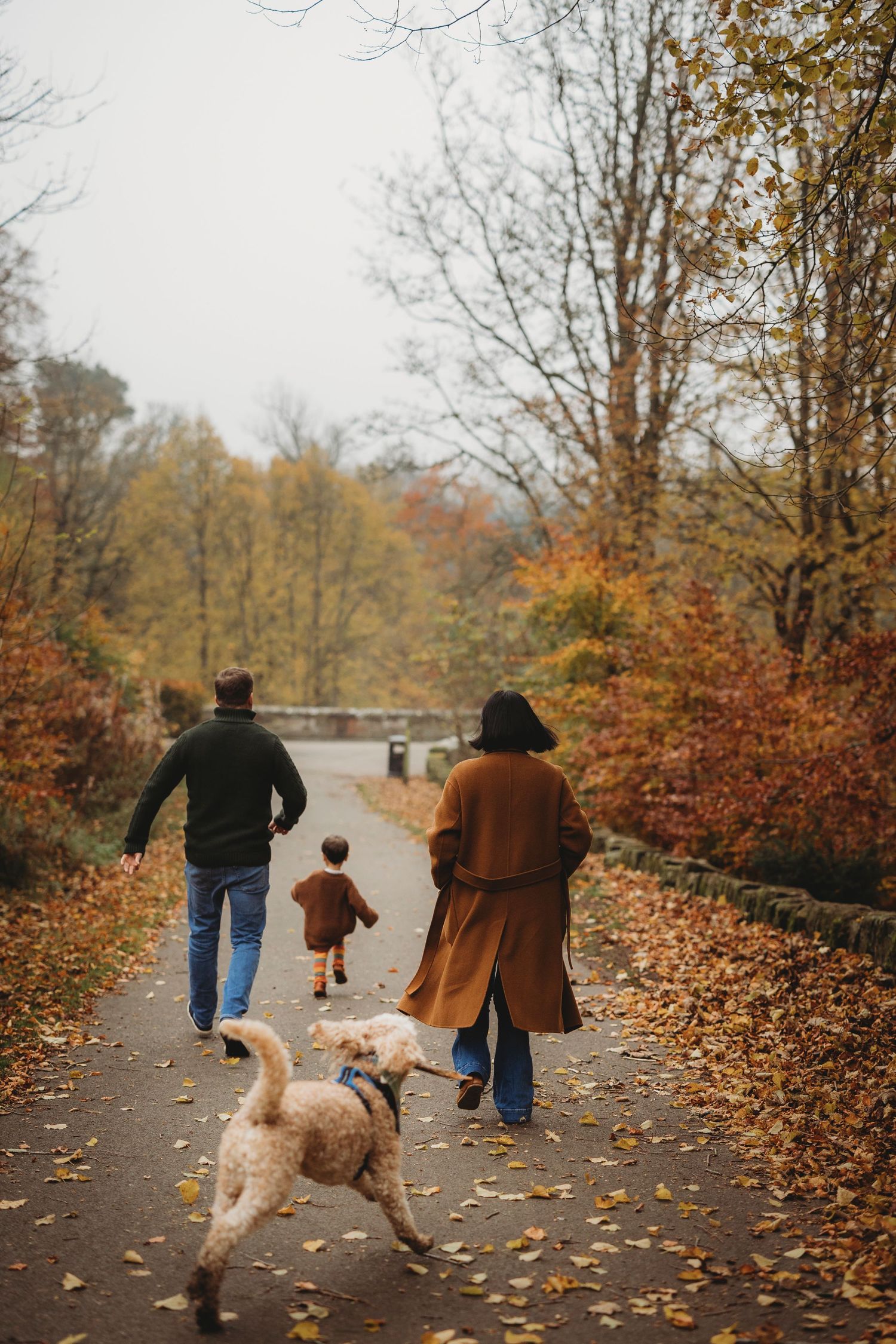 Two people enjoying a playful moment in a park filled with autumn leaves.