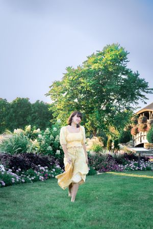 A dreamy garden scene with flowing yellow dress against lush landscaping.