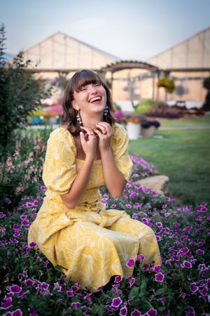 A joyful moment captured in a garden with yellow dress and purple flowers.