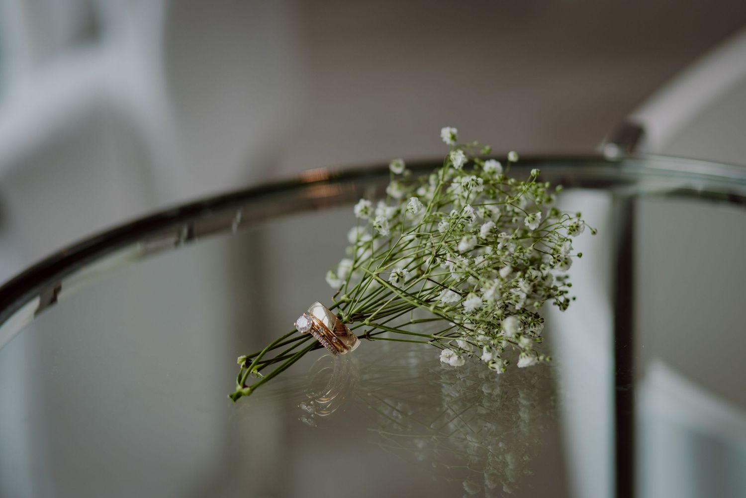 Delicate baby's breath flower arrangement in glass container on reflective surface.