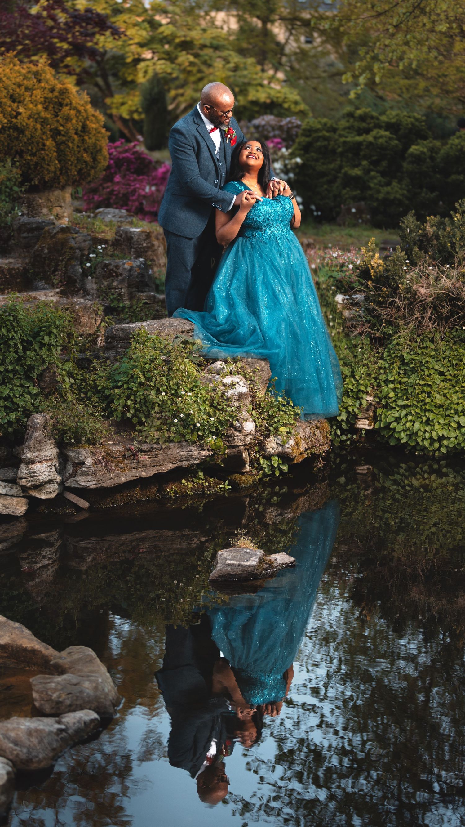 Couple by a garden pond with water reflection, bride in turquoise dress, romantic wedding photography Southampton