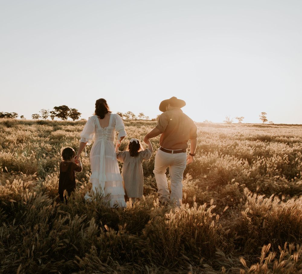 People walking through a golden field at sunset with vintage car in background. family, photographed in the blue mountains
