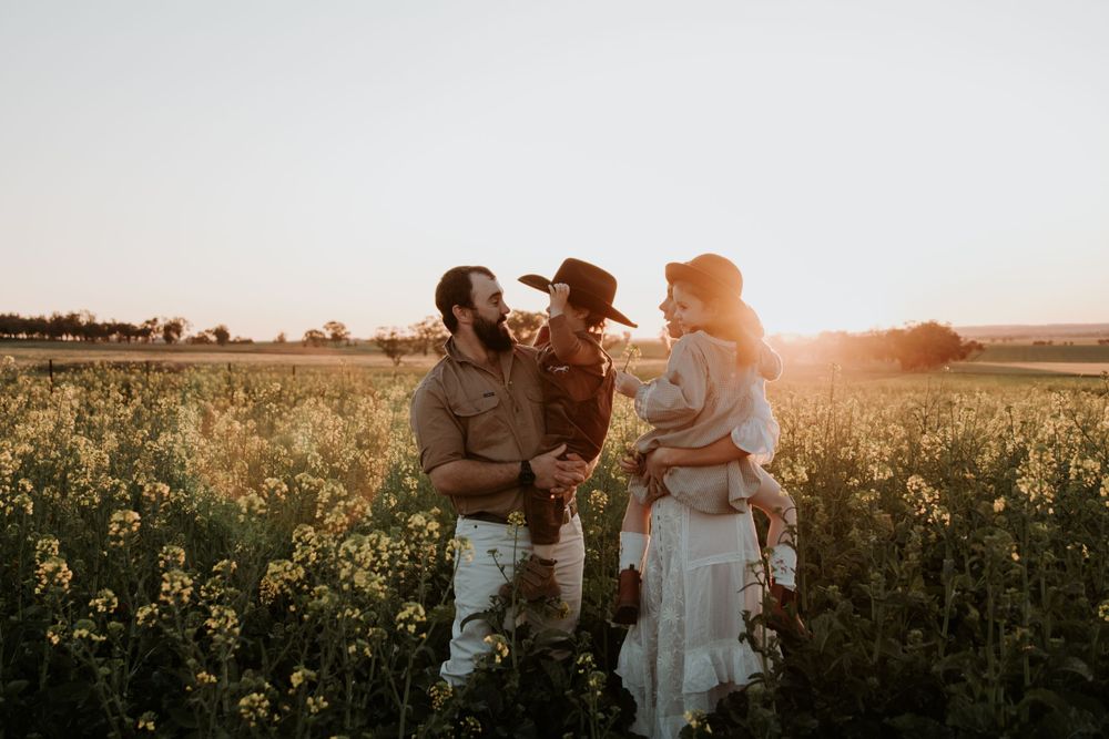 Silhouettes of family enjoying sunset in a rural field with vintage automobile.