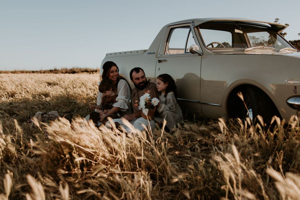 Vintage car parked in golden field during sunset photoshoot.