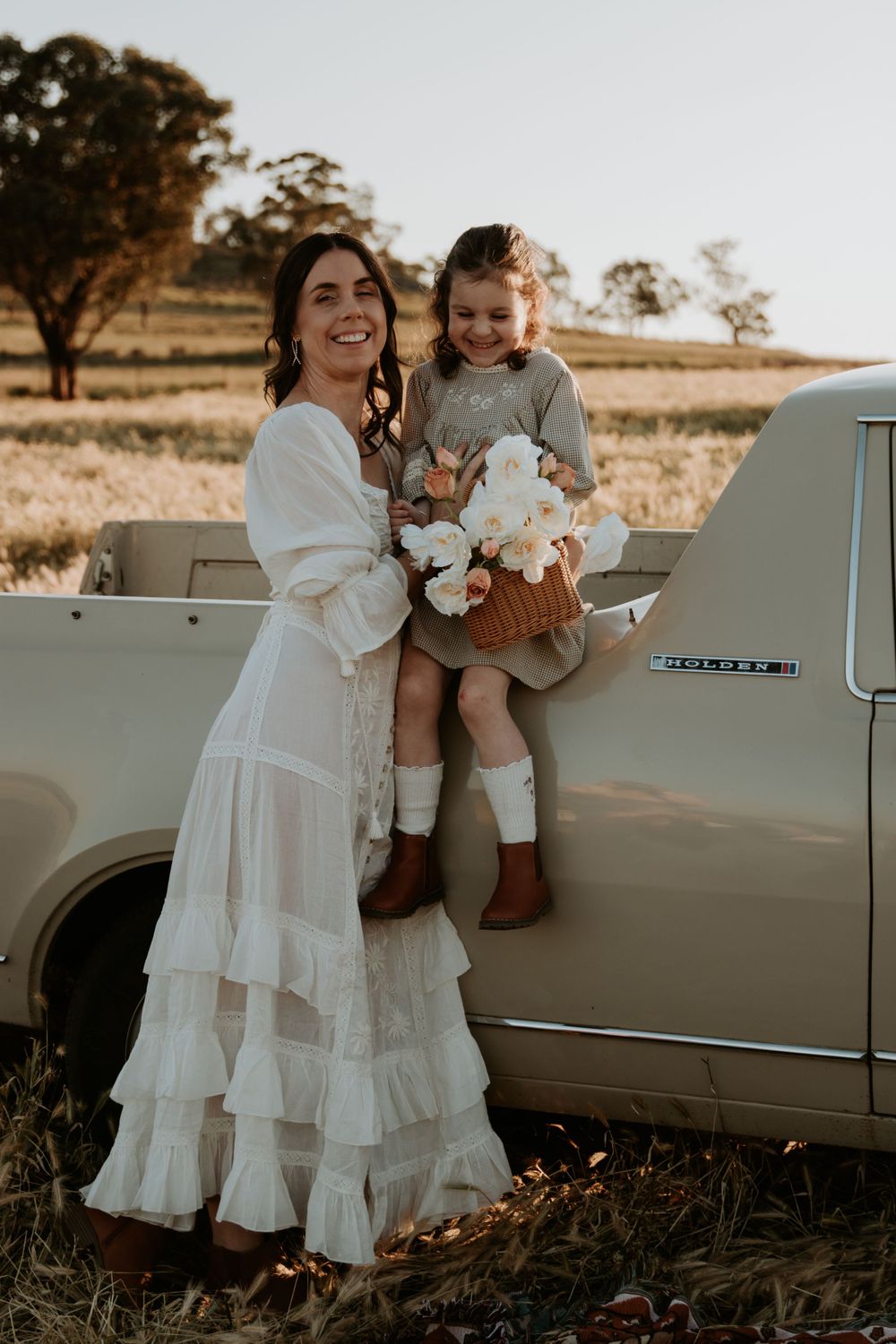 Family portrait session with classic car in rustic field setting.