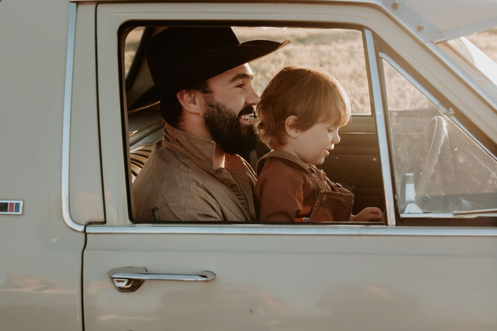 View through vintage car windows showing interior details during sunset photoshoot.
Dad and son, having fun and bonding during photoshoot