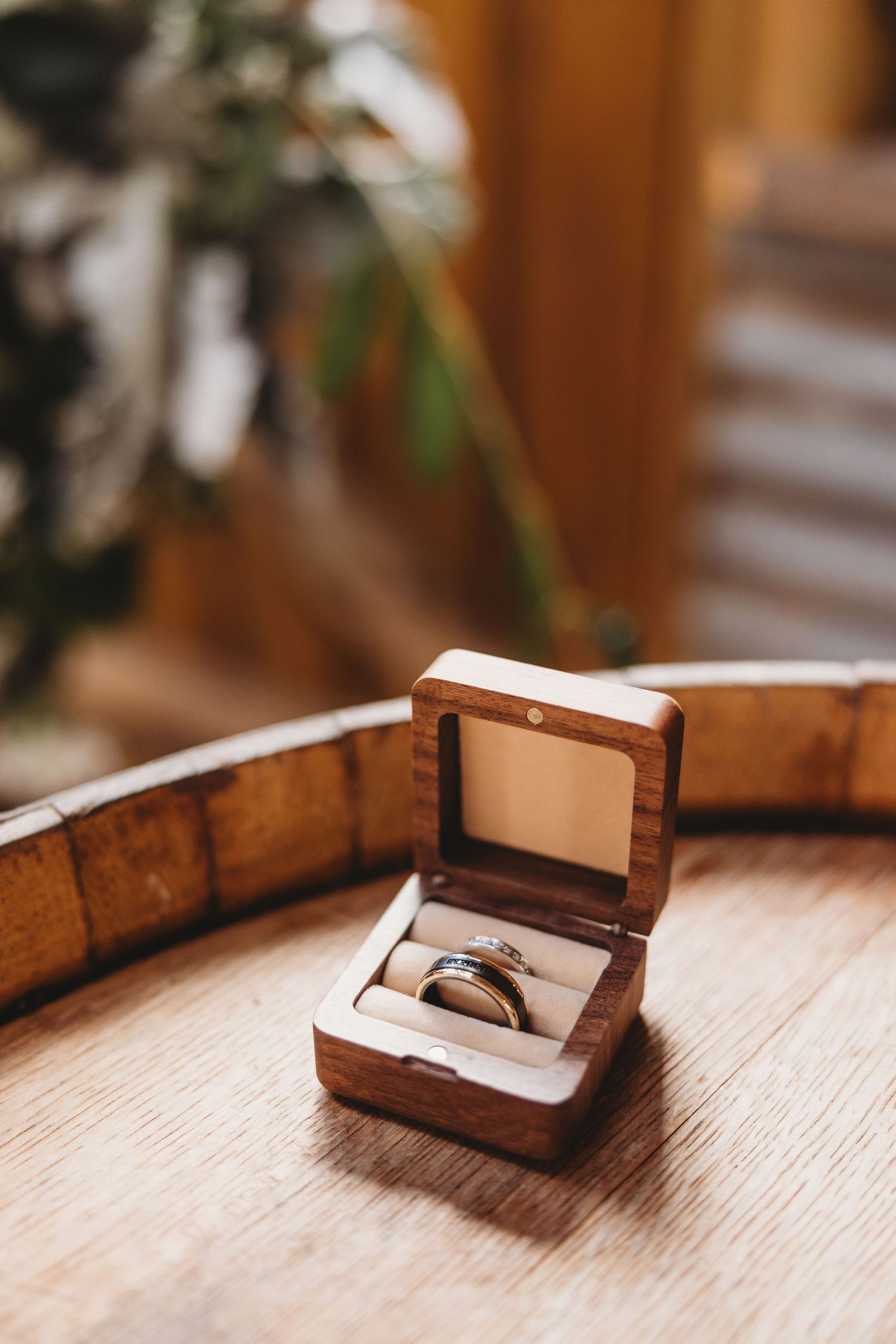 Wedding rings displayed in small wooden box on wooden surface.