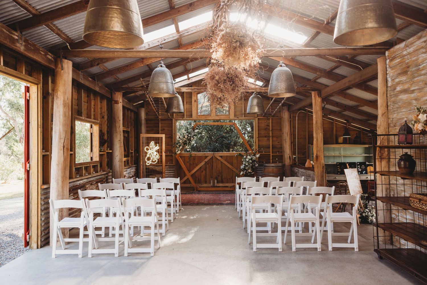 Rustic barn wedding venue with wooden beams and white chairs set up for ceremony.